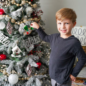 boy standing by Christmas tree holding dove ornament craft